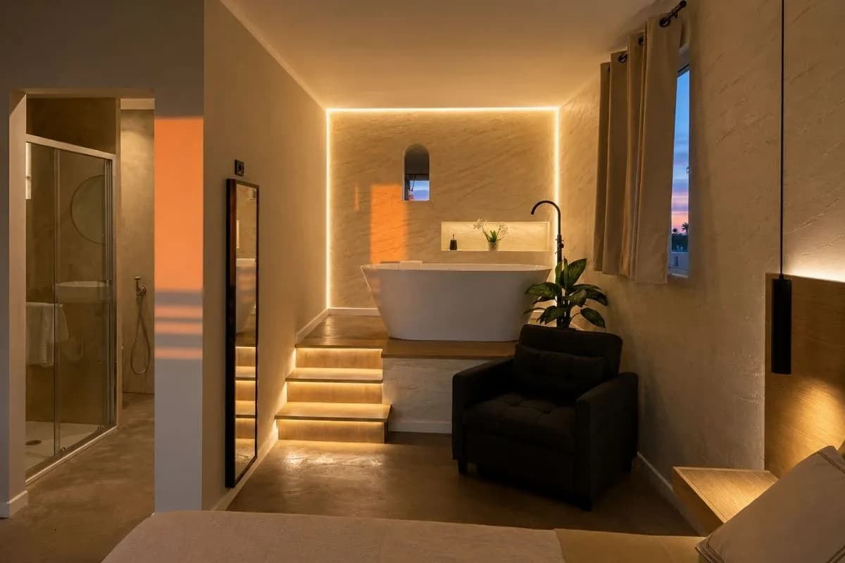 La camera al tramonto: la vasca freestanding sul podio e il bagno con doccia