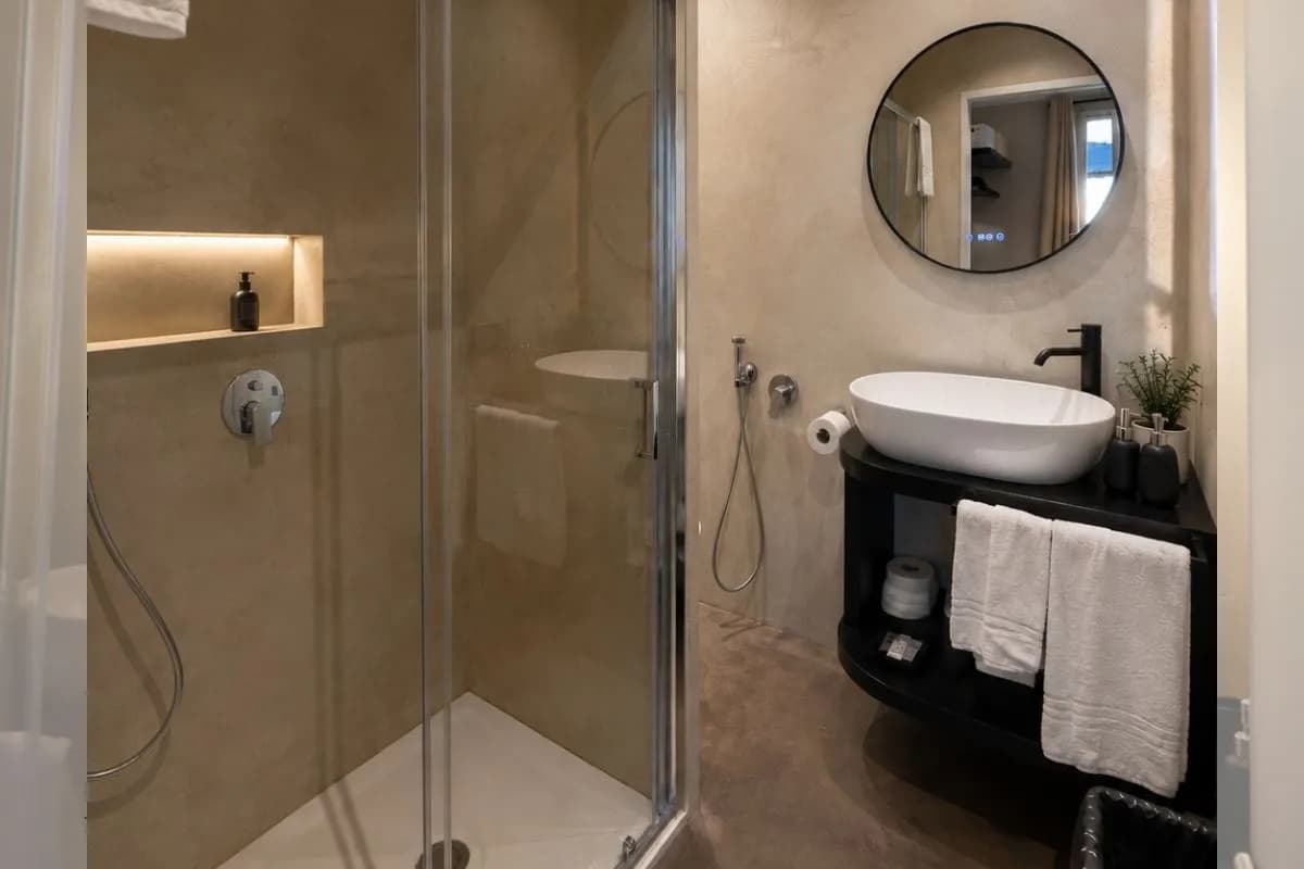 Il bagno privato con box doccia, lavabo d'appoggio e specchio tondo retroilluminato