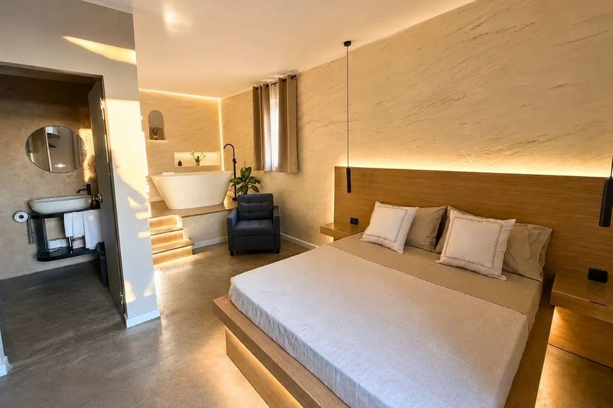 La camera della Suite: letto matrimoniale su pedana in legno e vasca freestanding sul podio rialzato